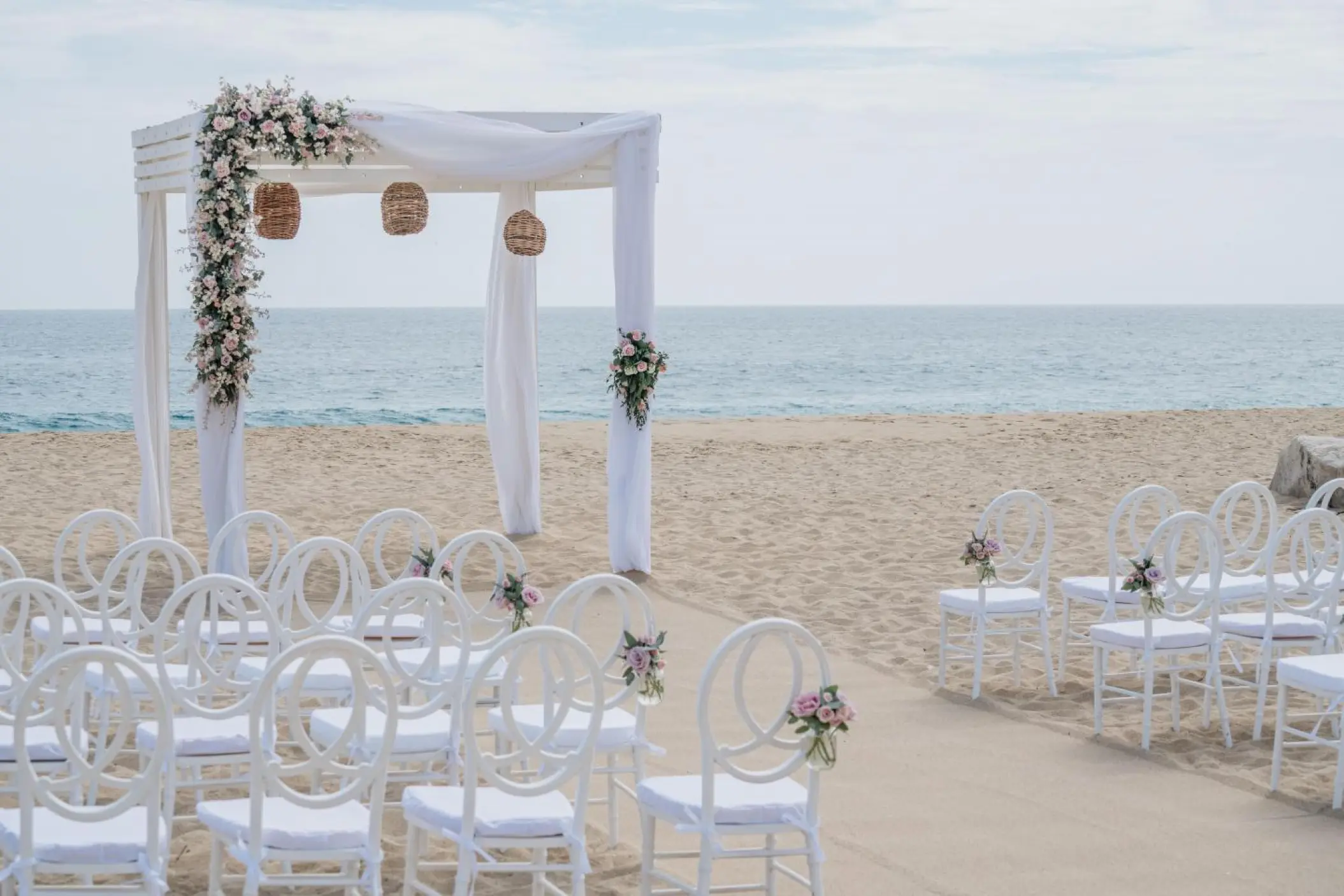 Beachfront wedding ceremony with white huppah and chairs at Sandos Finisterra, Cabo San Lucas