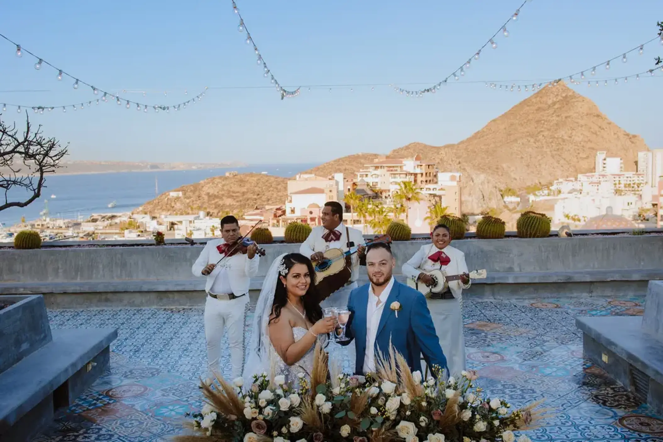 The bride and groom celebrating on the mountaintop terrace with a mariachi band at Sandos Finisterra, Cabo San Lucas