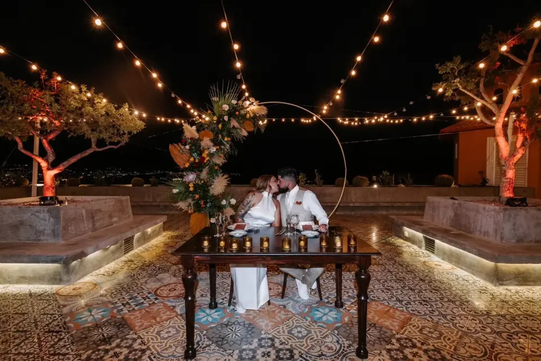 Couple kissing at a sweetheart table during a night reception at Sandos Finisterra, Cabo San Lucas