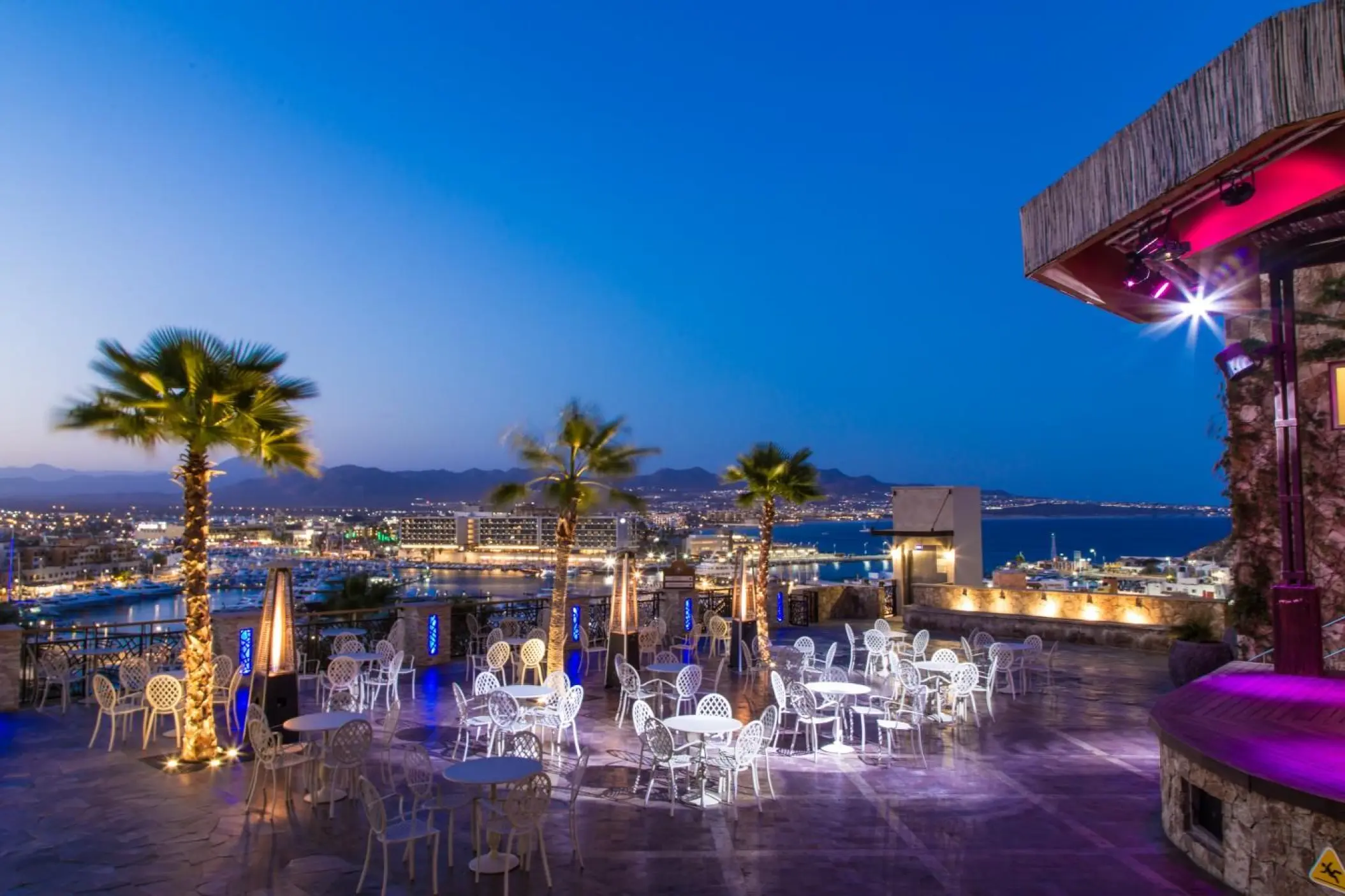 Outdoor terrace with cafe tables at night overlooking the marina at Sandos Finisterra, Cabo San Lucas