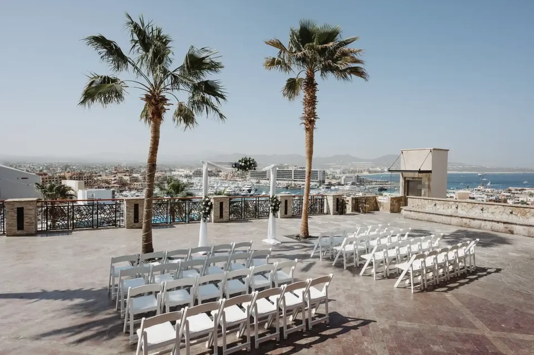 Plaza Finisterra wedding ceremony with white chairs overlooking the marina at Sandos Finisterra, Cabo San Lucas