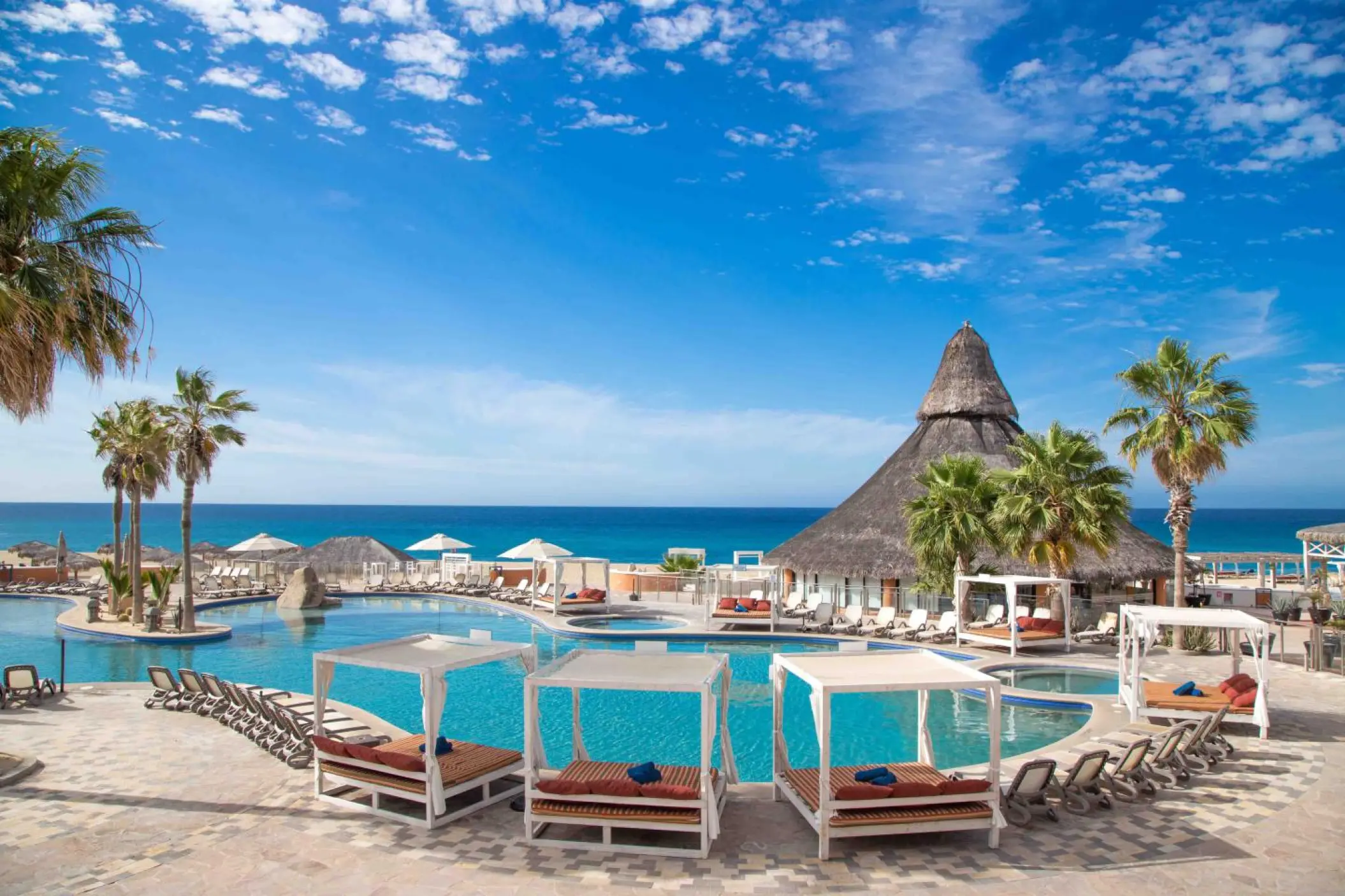 Outdoor swimming pool with cabanas and a palapa bar at Sandos Finisterra, Cabo San Lucas