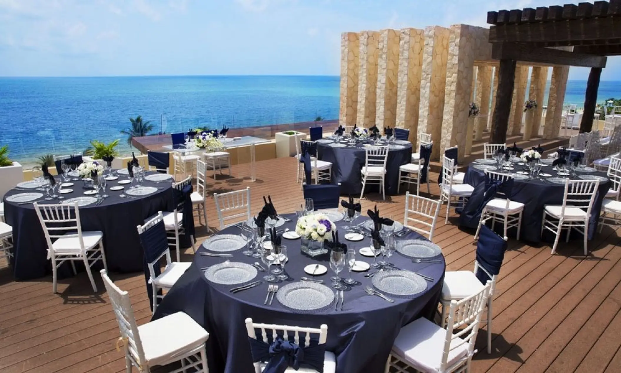 Terrace wedding reception with navy linens and white chairs at Royalton Riviera Cancun