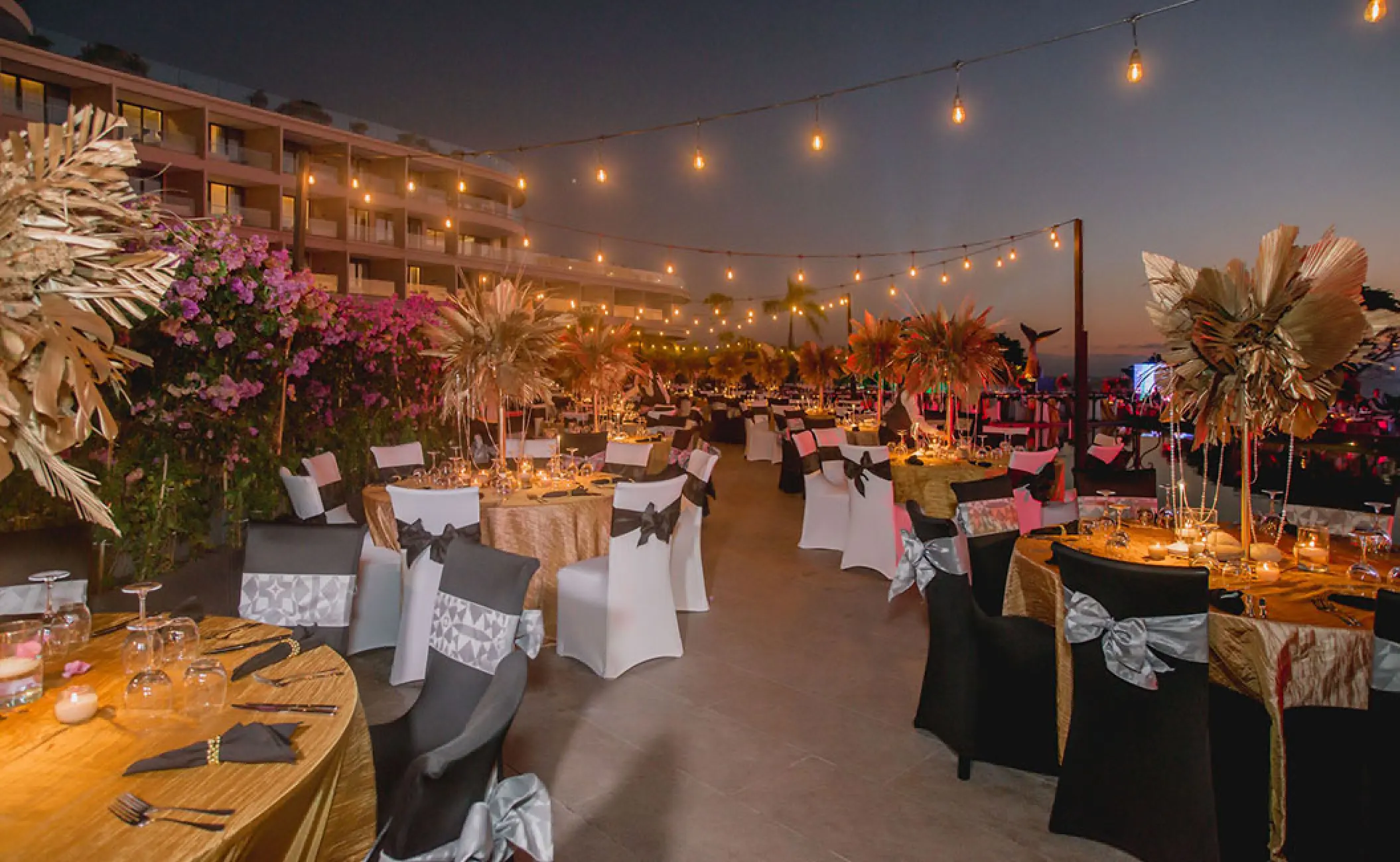 Outdoor wedding reception at Secrets Bahia Mita, Puerto Vallarta with gold tables and string lights at dusk