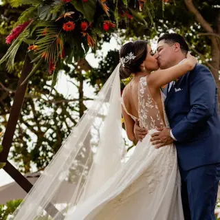 The bride and groom kissing under a floral arch at Secrets Bahia Mita, Puerto Vallarta