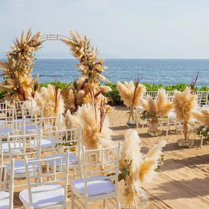 Sand terrace wedding ceremony with pampas grass arch and white chairs at Secrets Bahia Mita, Puerto Vallarta