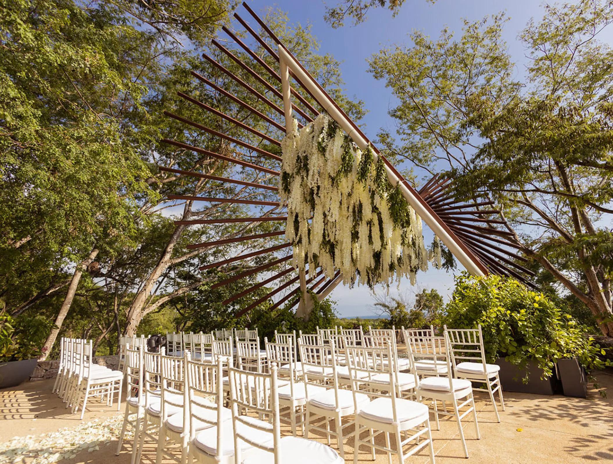 Outdoor wedding ceremony setup with white chairs and floral installation at Secrets Bahia Mita, Puerto Vallarta