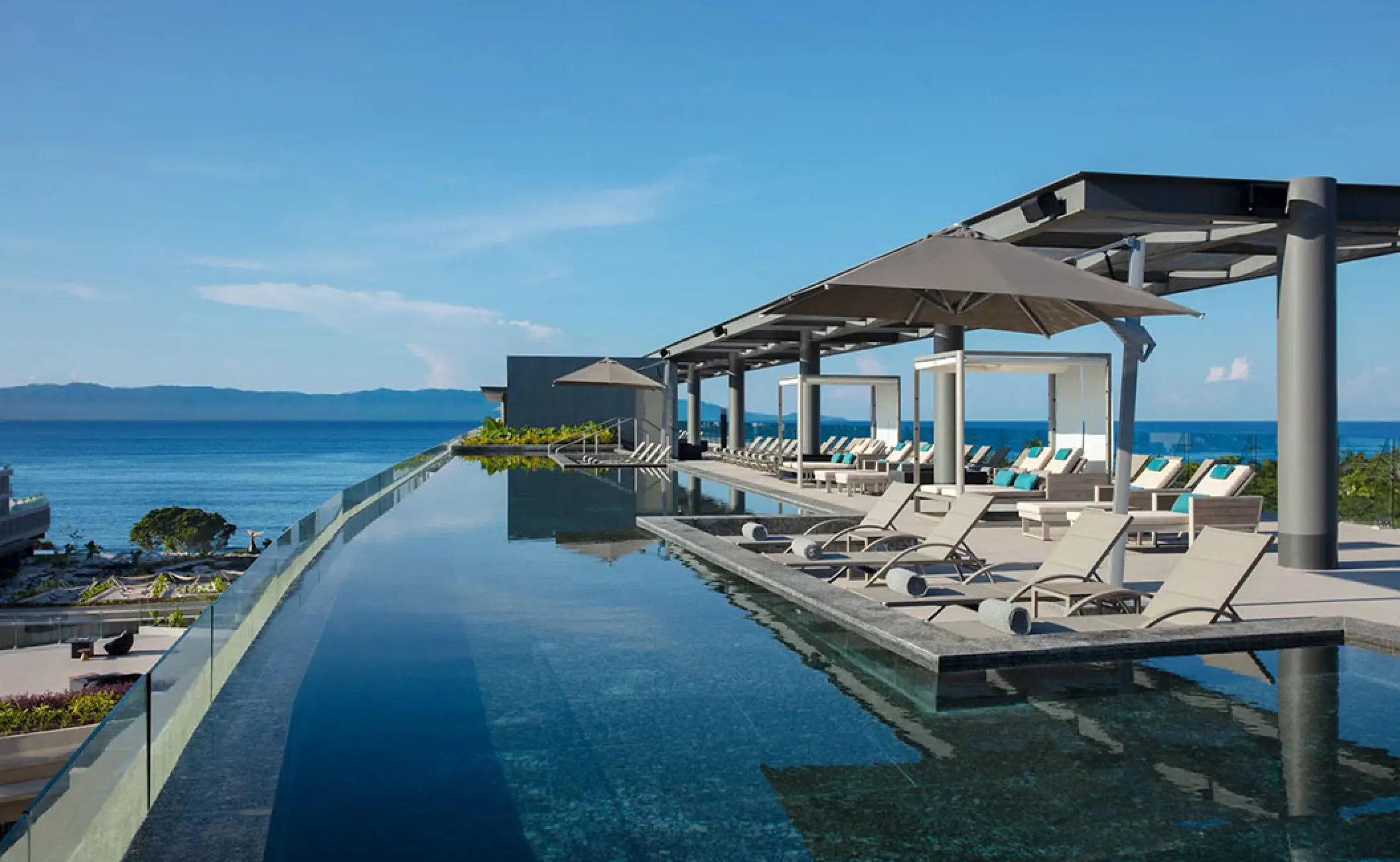 Rooftop infinity pool and sun loungers overlooking the ocean at Secrets Bahia Mita, Puerto Vallarta
