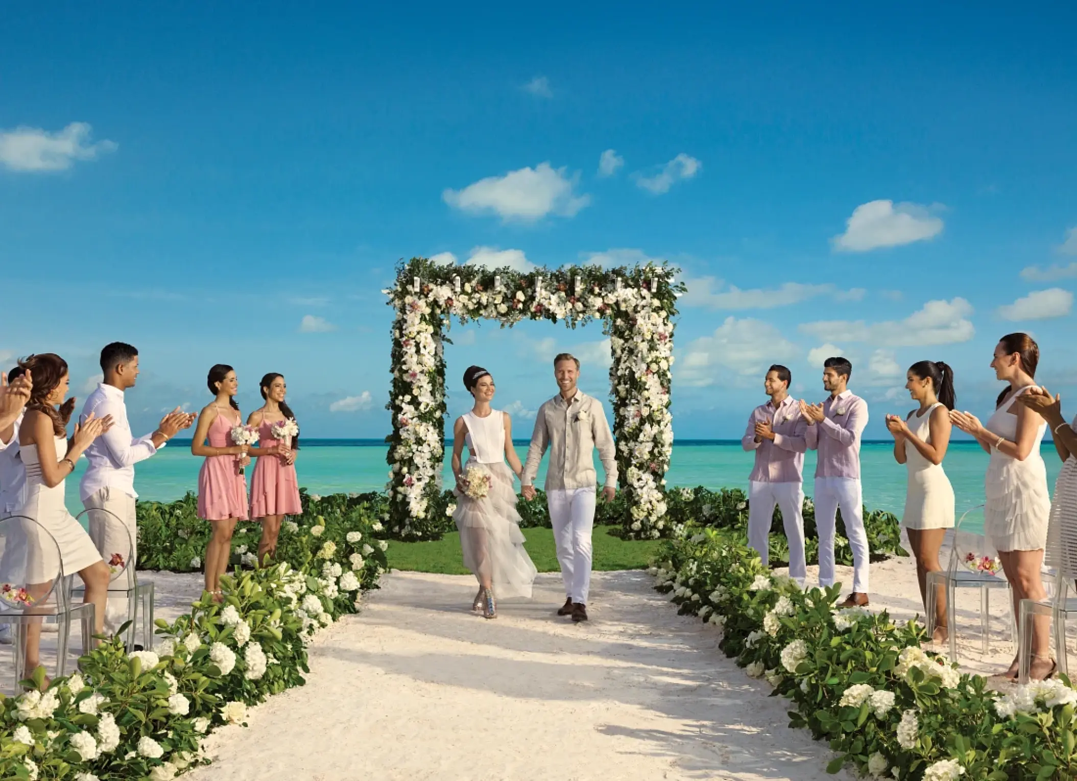 The couple walking down a flower-lined aisle after their beach ceremony at Secrets Maroma Beach, Riviera Maya