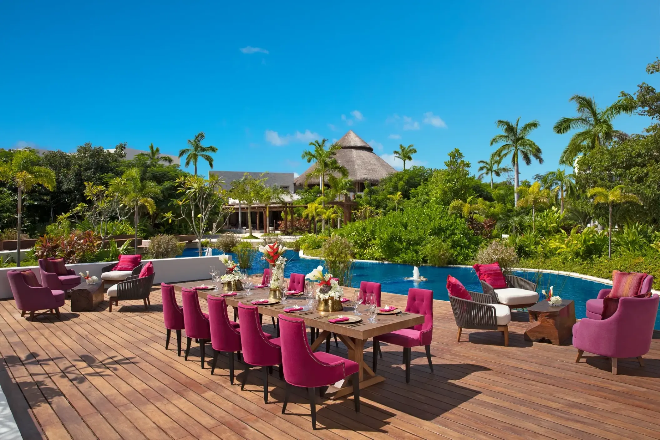 Outdoor wedding reception with magenta chairs on a wooden deck at Secrets Akumal, Riviera Maya