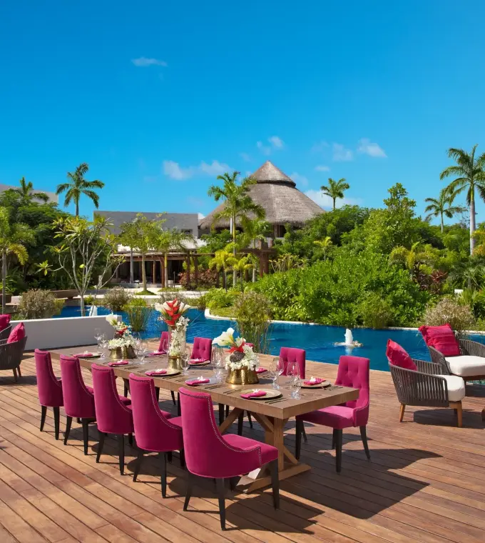 Outdoor wedding reception with magenta chairs on a wooden deck at Secrets Akumal, Riviera Maya