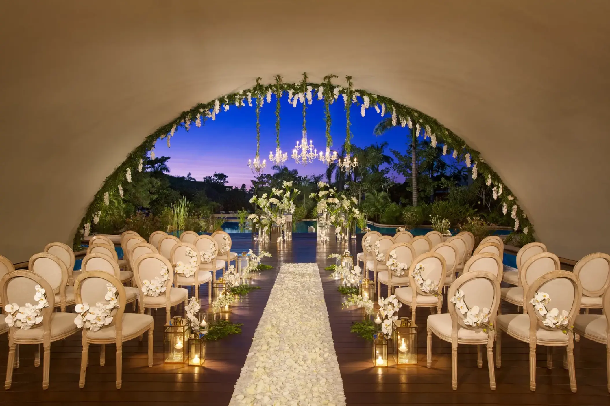 Indoor wedding ceremony with floral arch and chandeliers at Secrets Akumal, Riviera Maya