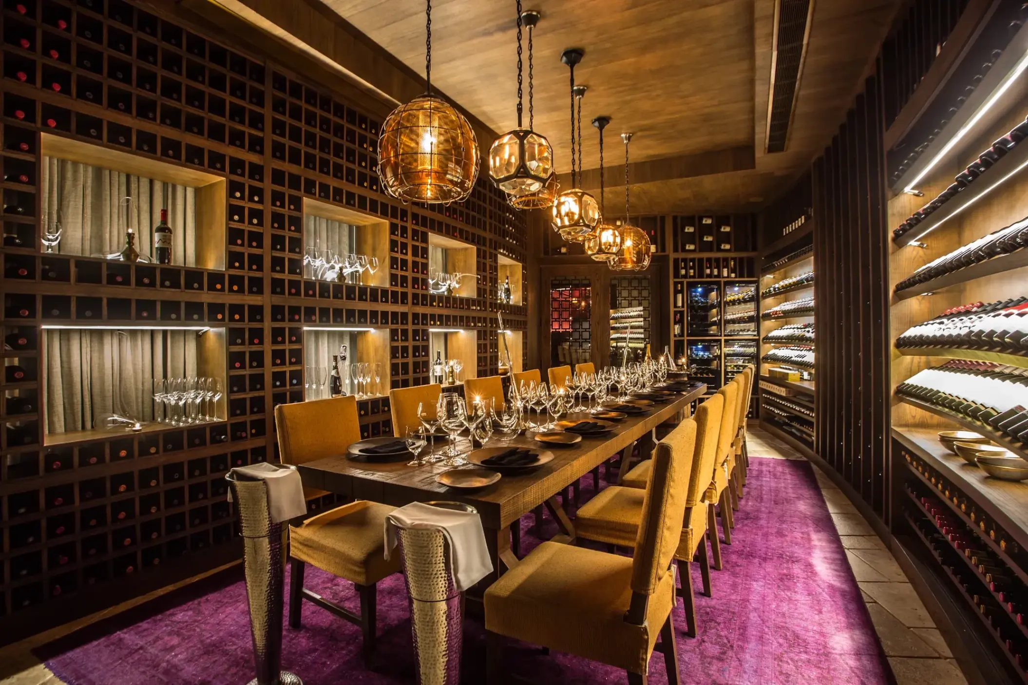 Private wine cellar dining room with a long table and gold chairs at Secrets Akumal, Riviera Maya