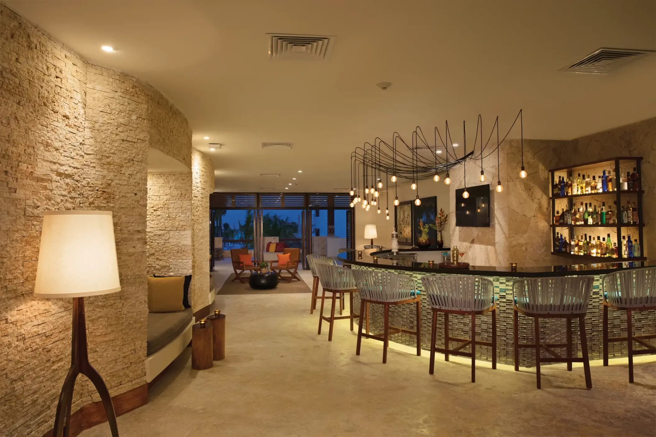 Rendezvous lobby bar with stone walls and modern lighting at Secrets Cap Cana, Punta Cana