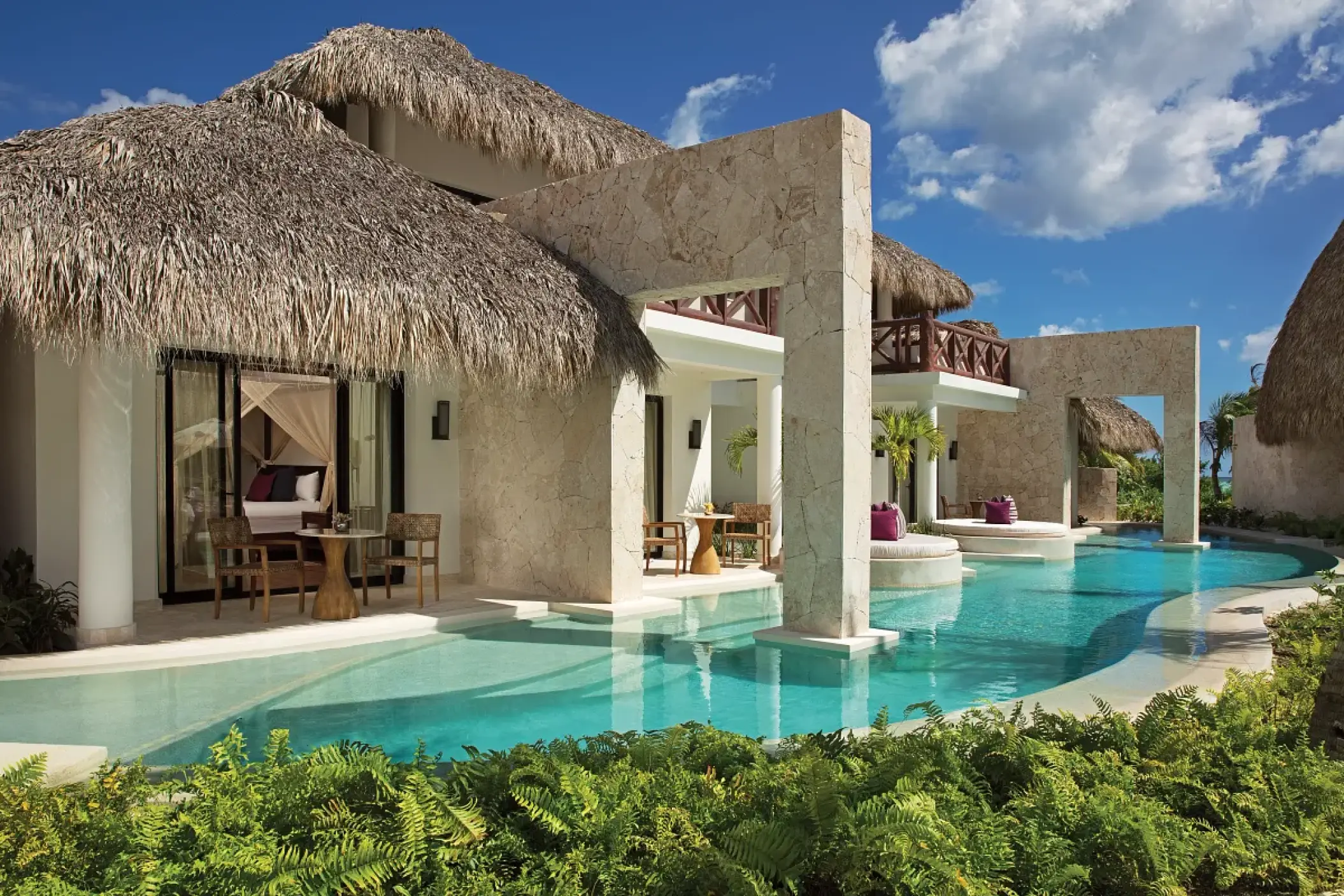 Swim-out suites with thatched roofs and stone pillars at Secrets Cap Cana, Punta Cana