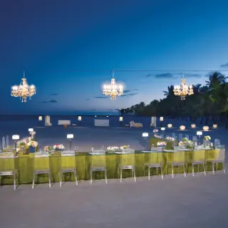Nighttime beach reception with chandeliers and clear chairs at Secrets Cap Cana, Punta Cana