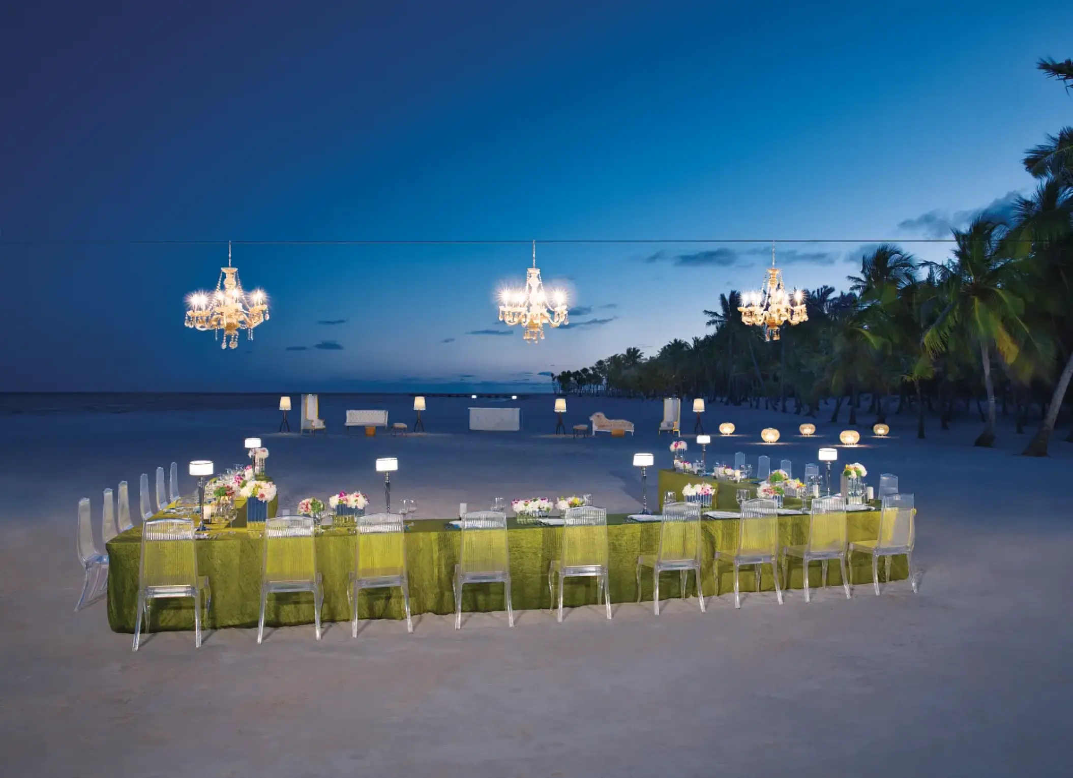 Nighttime beach reception with chandeliers and clear chairs at Secrets Cap Cana, Punta Cana