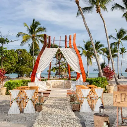 Beachfront wedding ceremony with a modern wood gazebo and white drapery at Secrets Cap Cana, Punta Cana