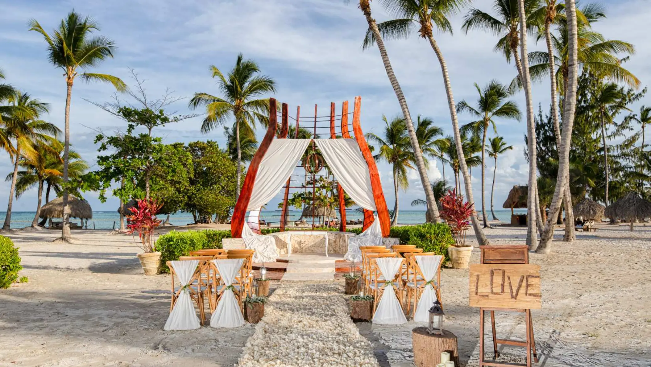 Beachfront wedding ceremony with a modern wood gazebo and white drapery at Secrets Cap Cana, Punta Cana