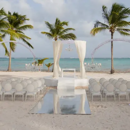 Juanillo Beach wedding ceremony setup with white floral arches and drapes at Secrets Cap Cana, Punta Cana