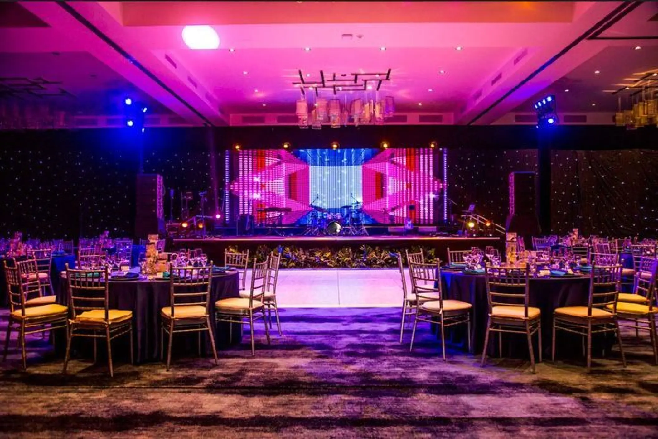 Indoor ballroom wedding reception with purple lighting and stage at Secrets Cap Cana, Punta Cana