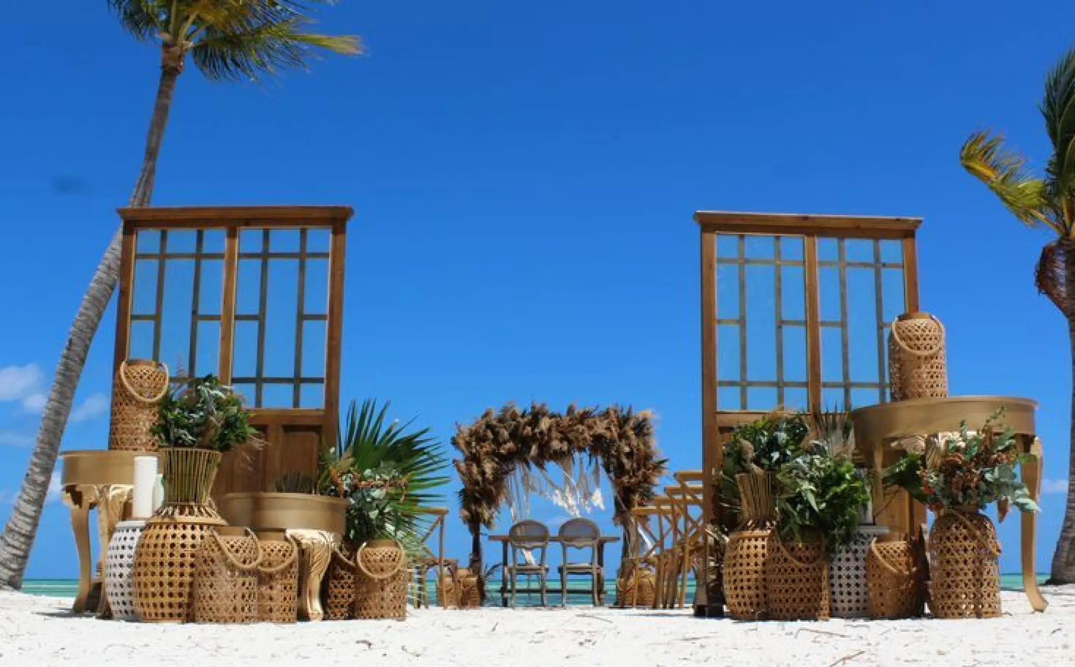 Beach wedding ceremony setup with wicker lanterns and wooden doors at Secrets Cap Cana, Punta Cana