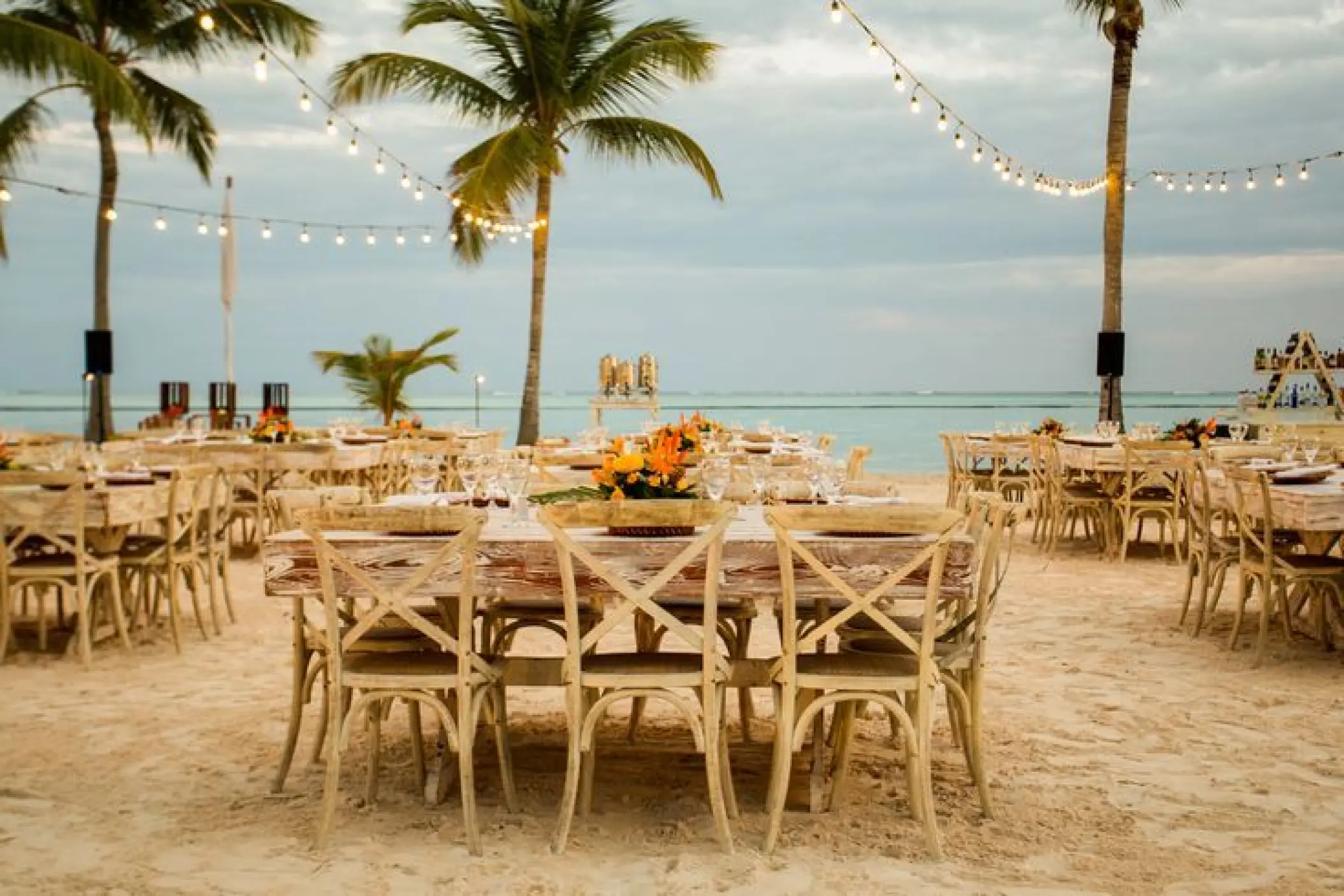 Beachfront wedding reception with string lights and wooden tables at Secrets Cap Cana, Punta Cana