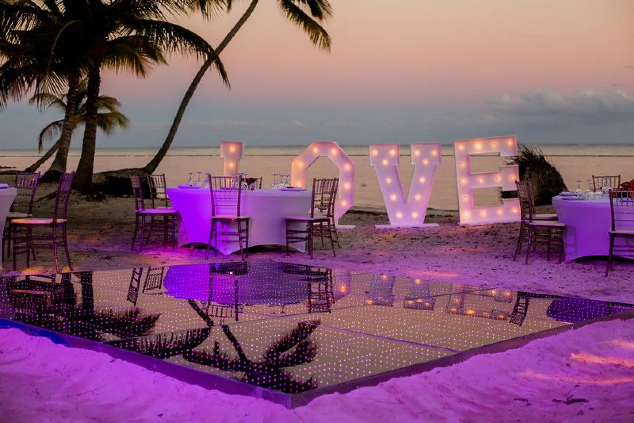 Beachfront wedding reception with lighted LOVE sign and dance floor at Secrets Cap Cana, Punta Cana