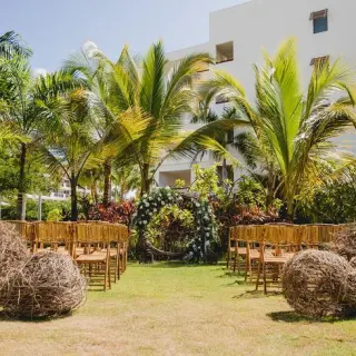 Garden terrace wedding ceremony with floral arch and wooden chairs at Secrets Cap Cana, Punta Cana
