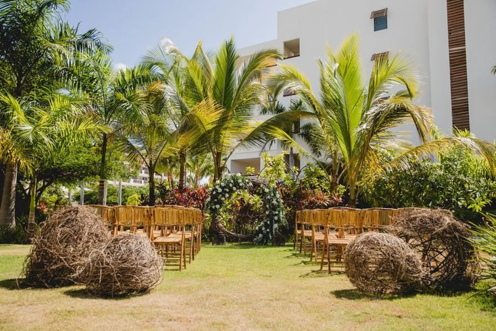 Garden terrace wedding ceremony with floral arch and wooden chairs at Secrets Cap Cana, Punta Cana
