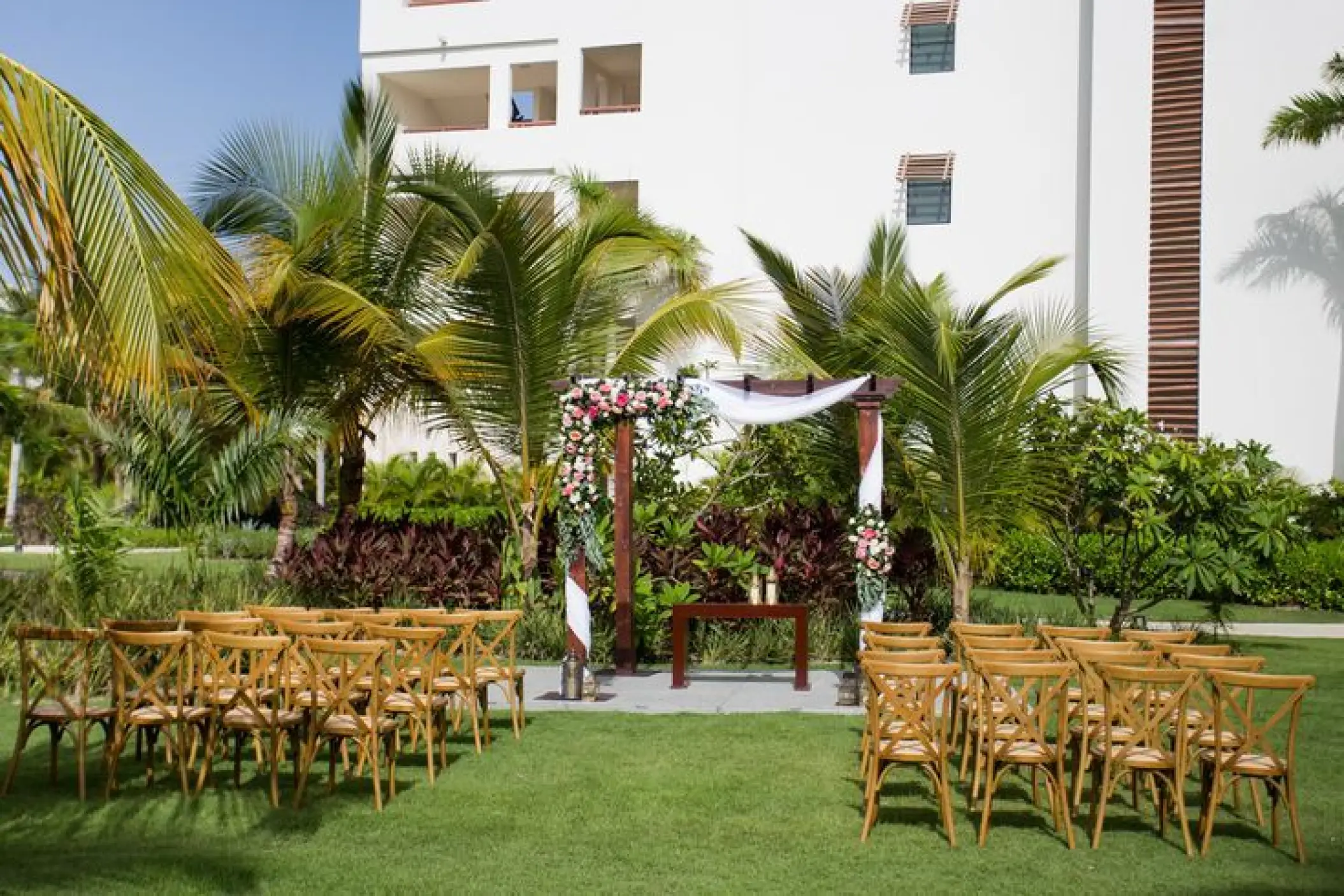 Garden terrace wedding ceremony setup with floral wooden arch at Secrets Cap Cana, Punta Cana