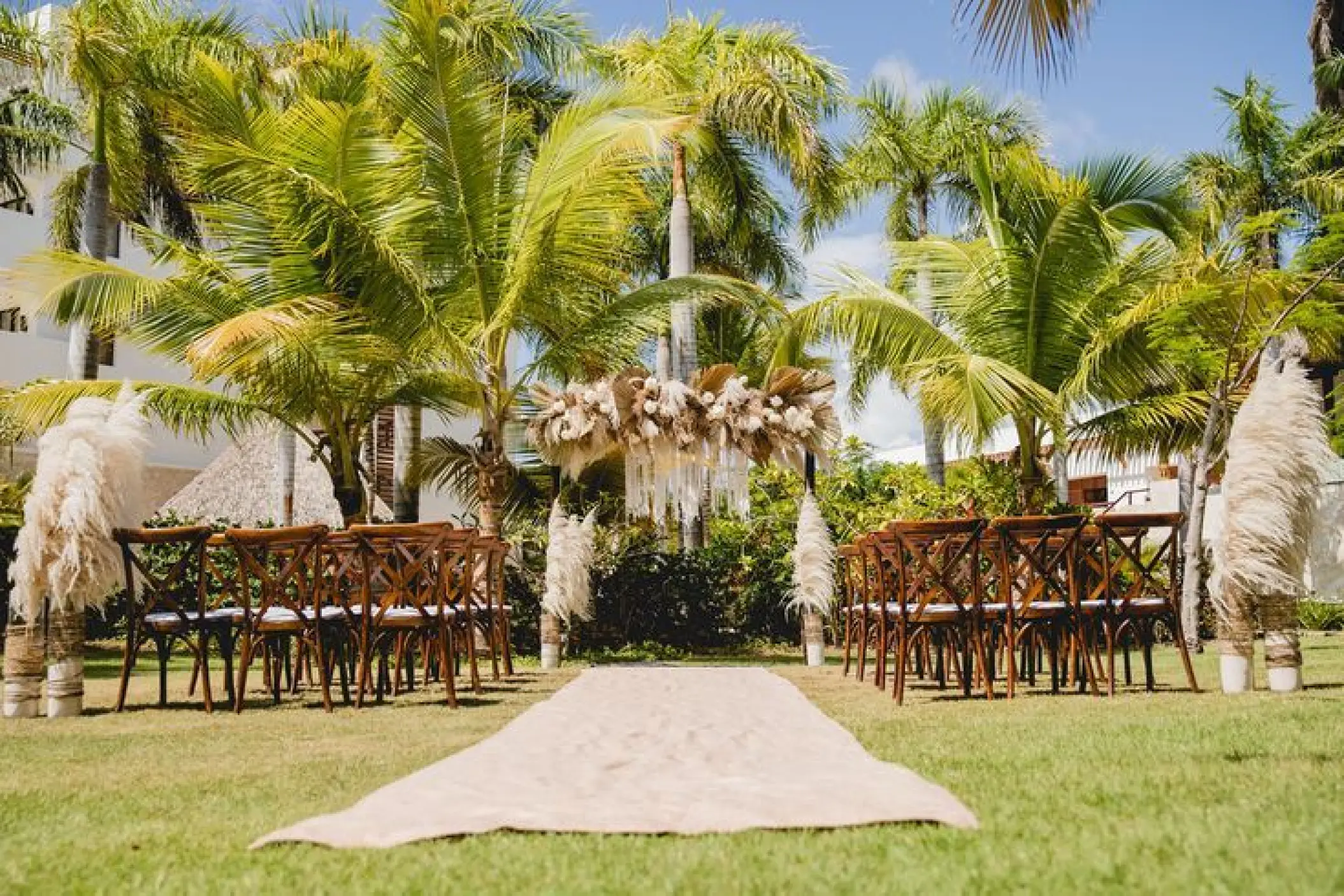Garden wedding ceremony setup with pampas grass and cross-back chairs at Secrets Cap Cana, Punta Cana