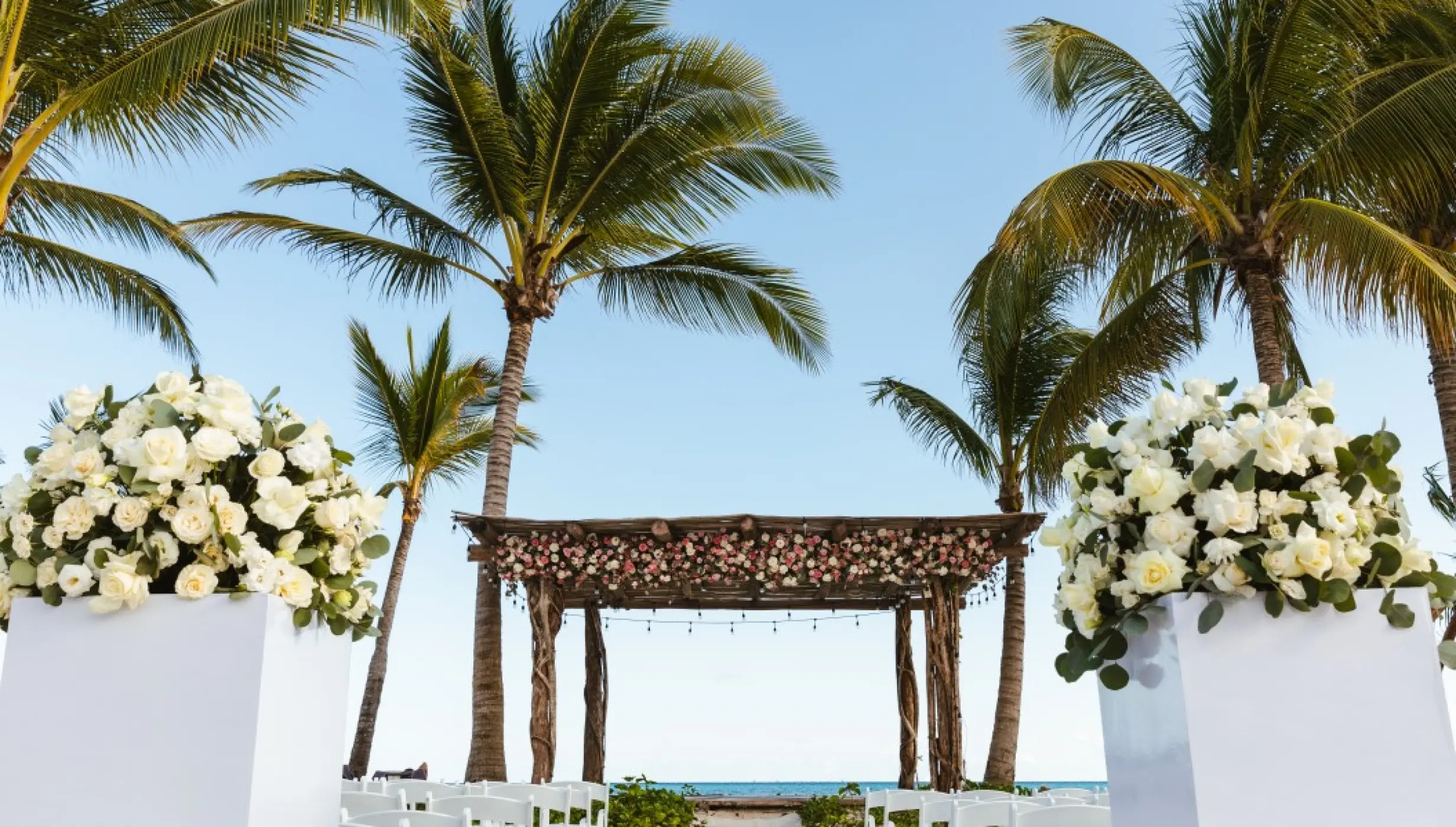Beachfront wedding ceremony with a rustic floral gazebo and white roses at Impression Moxché by Secrets, Playa Del Carmen