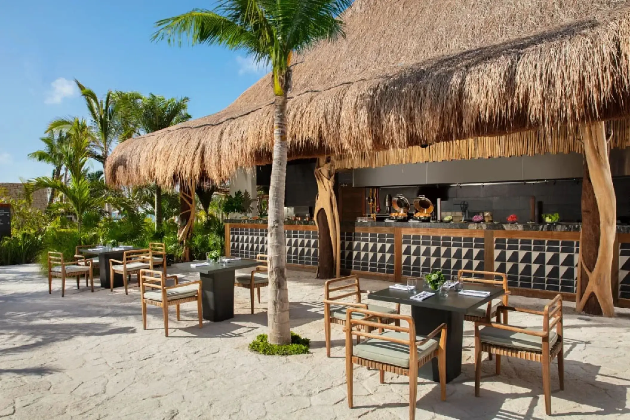 Outdoor seating at the Barefoot Grill under a thatched roof at Secrets Moxche, Playa Del Carmen