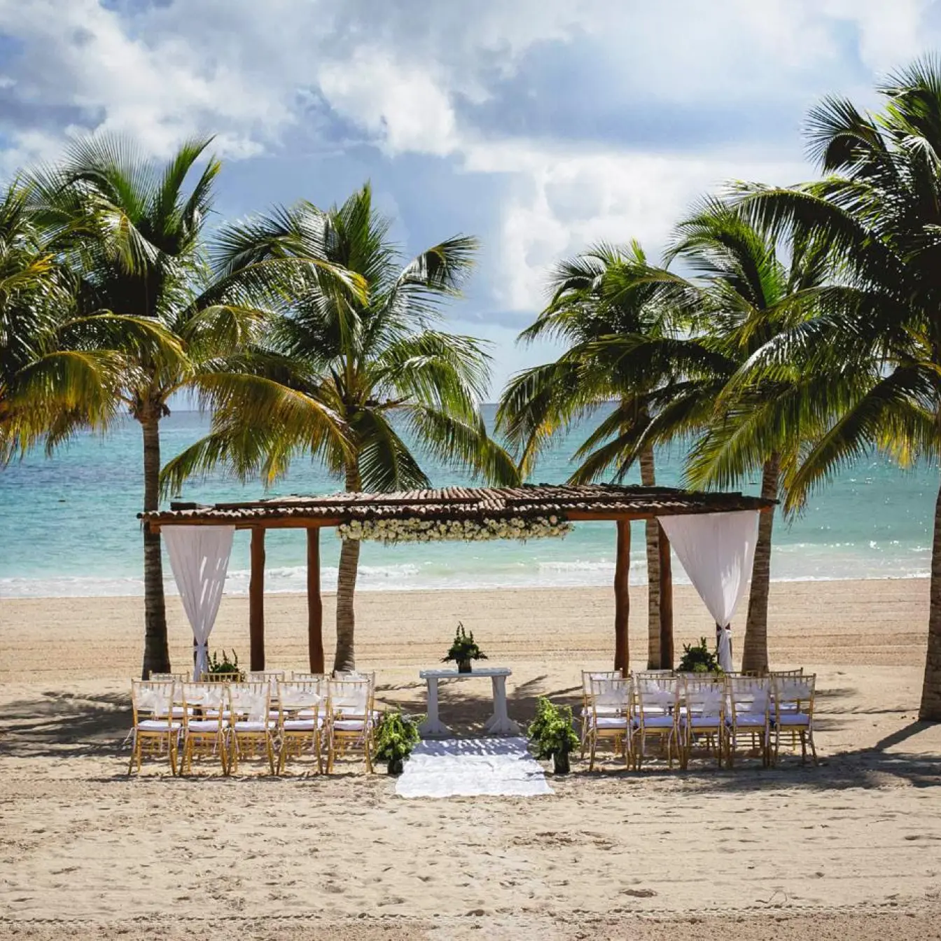 Beachfront wedding ceremony setup under palm trees at Secrets Maroma Beach, Riviera Maya