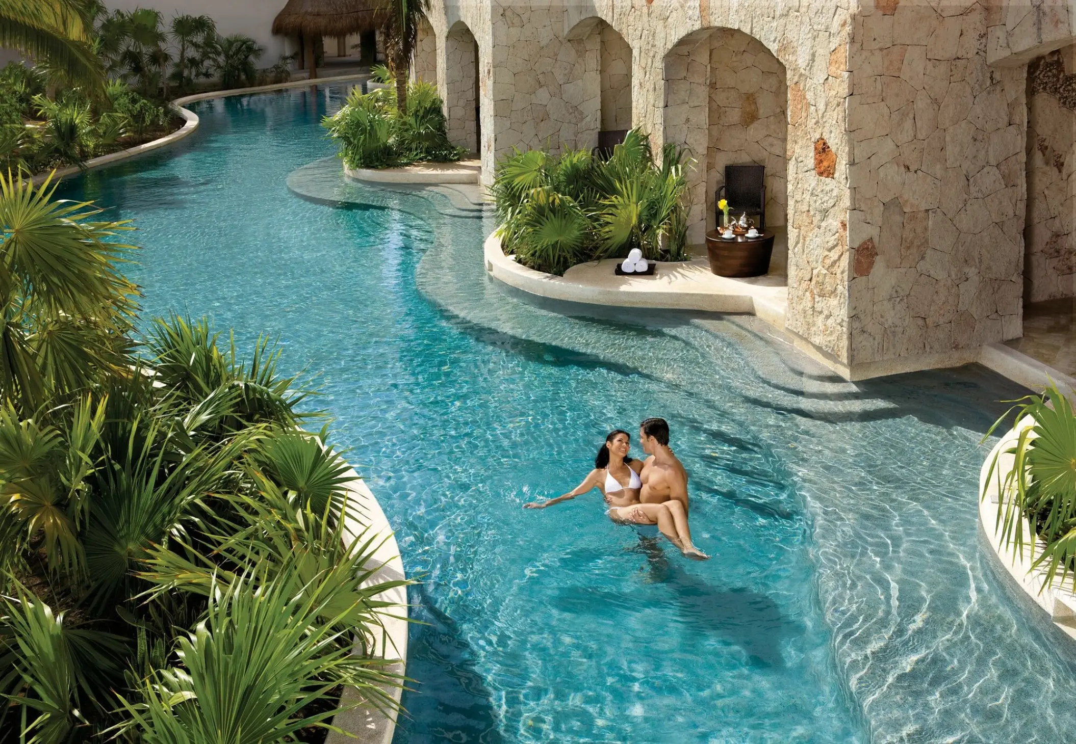 Couple relaxing in a swim-out pool at Secrets Maroma Beach, Riviera Maya