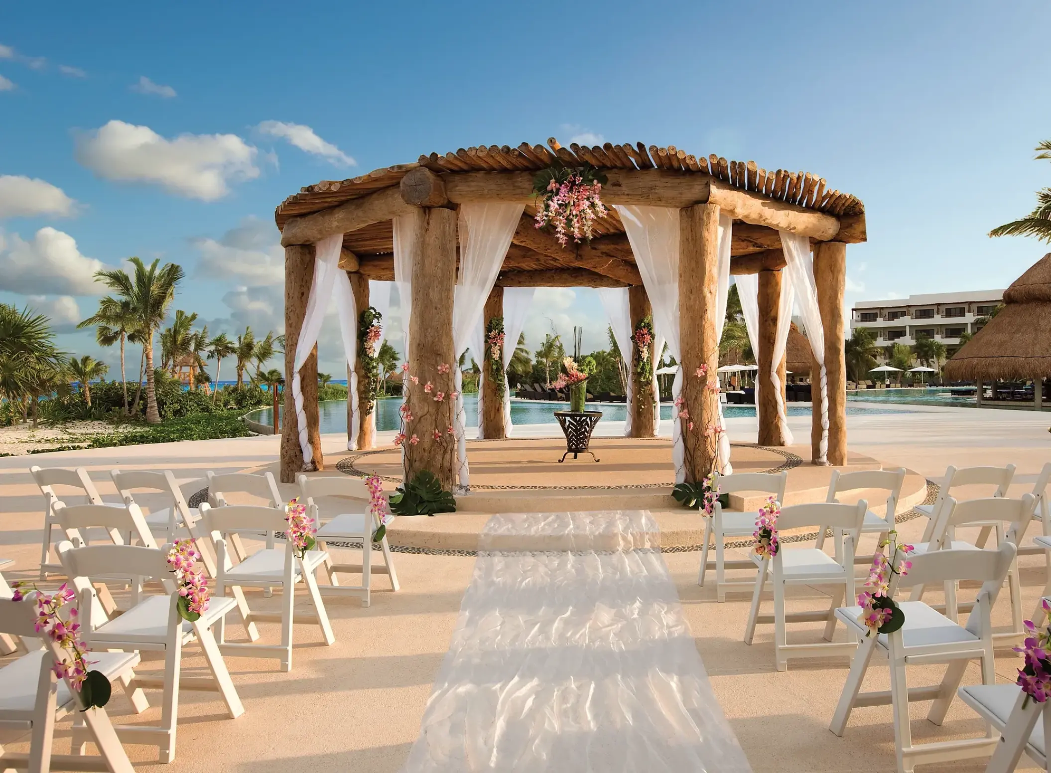 Rustic wooden gazebo wedding ceremony with white chairs at Secrets Maroma Beach, Riviera Maya