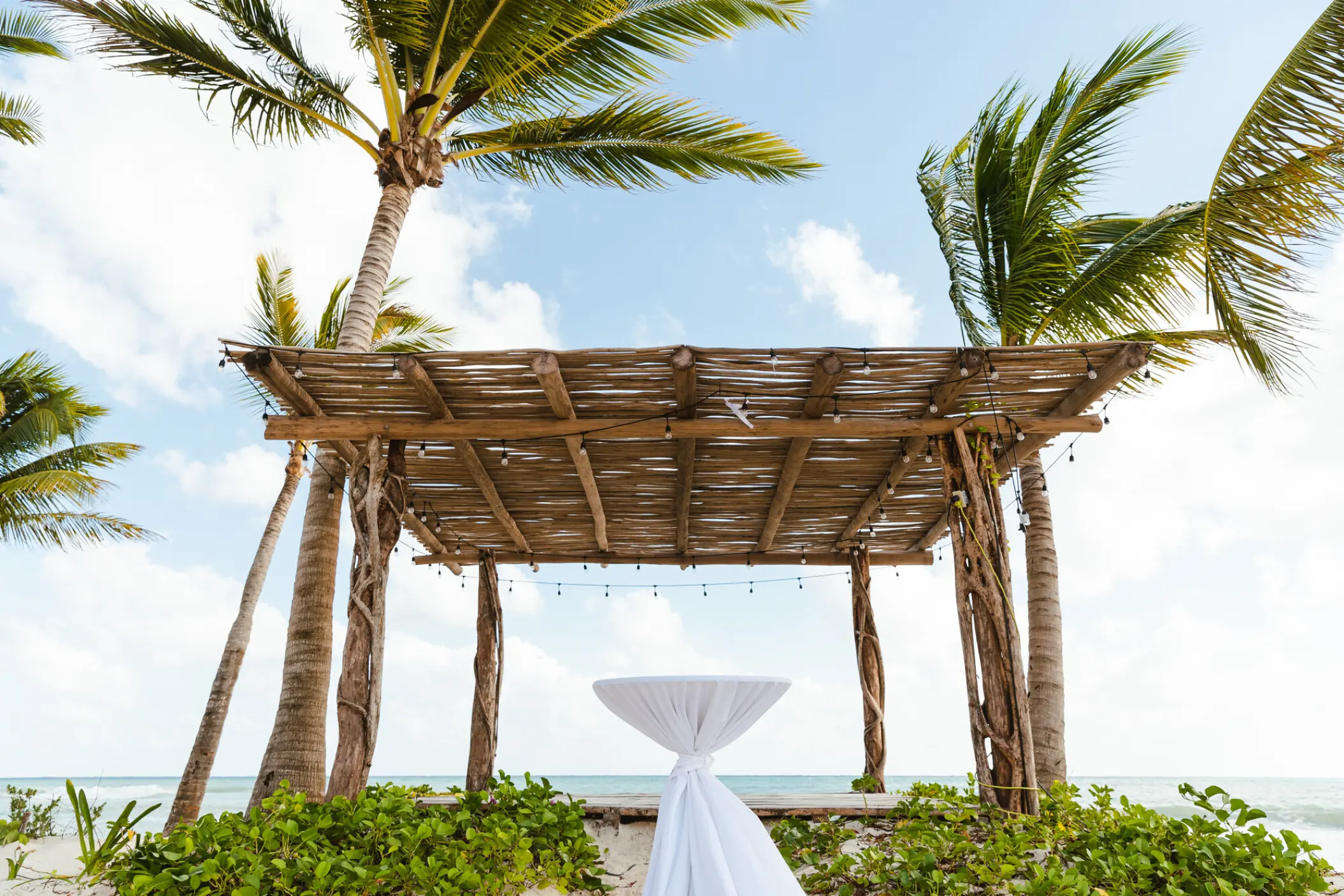 Wooden beach ceremony gazebo under palm trees at Secrets Moxche, Playa Del Carmen