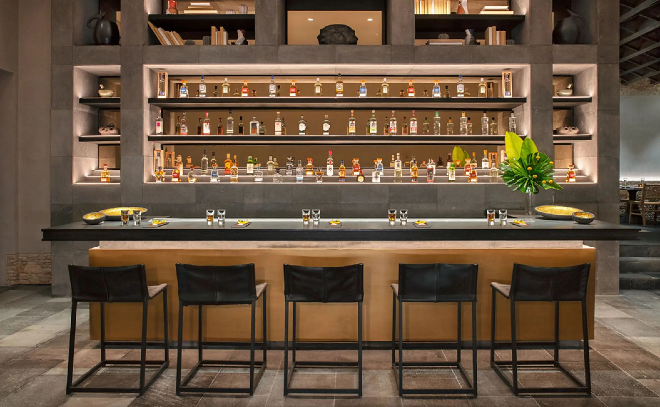 Dos Almas bar area with modern stone shelving and leather stools at Secrets Moxche, Playa Del Carmen