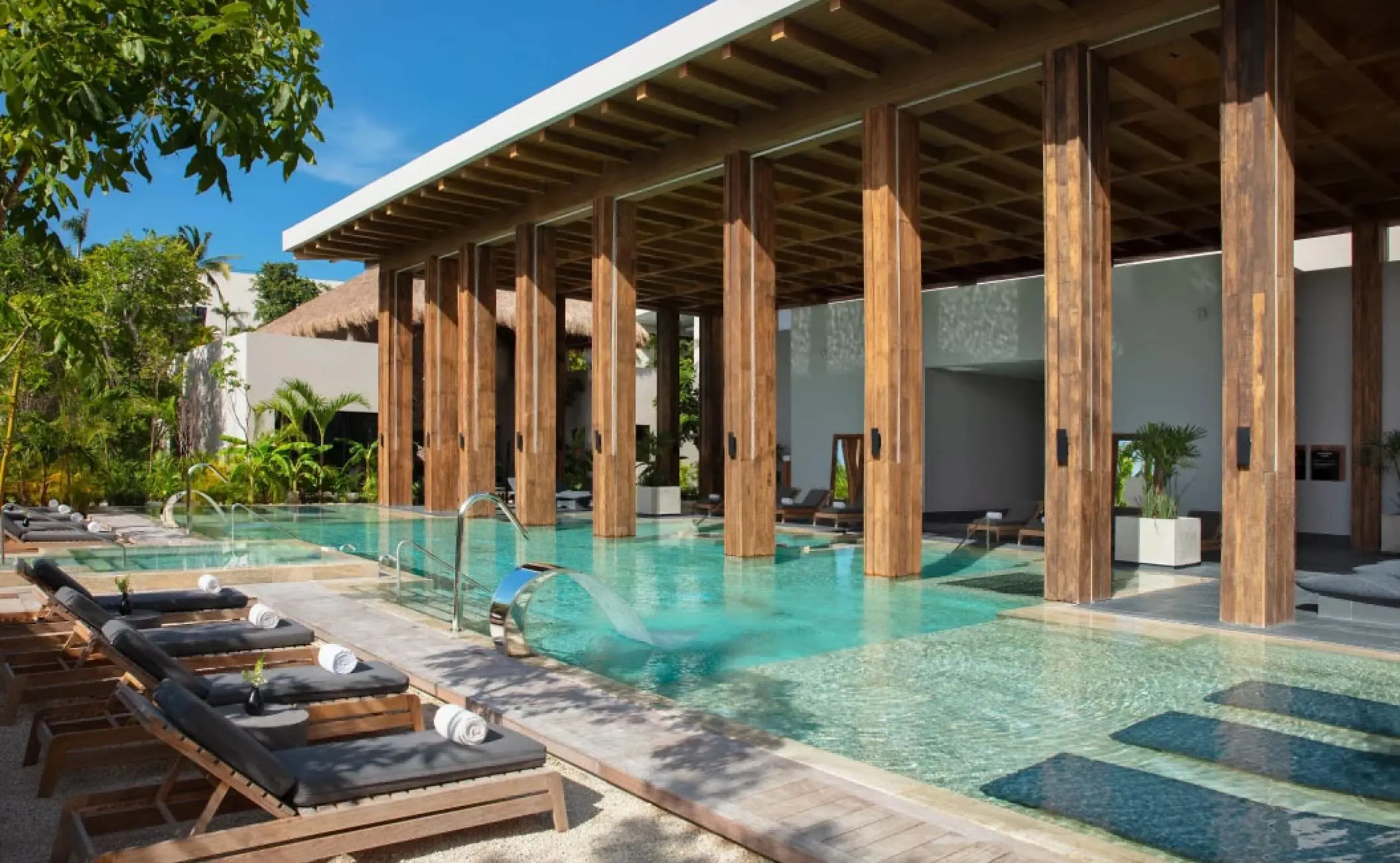 Hydrotherapy pool with lounge chairs and wooden columns at Secrets Moxche, Playa Del Carmen