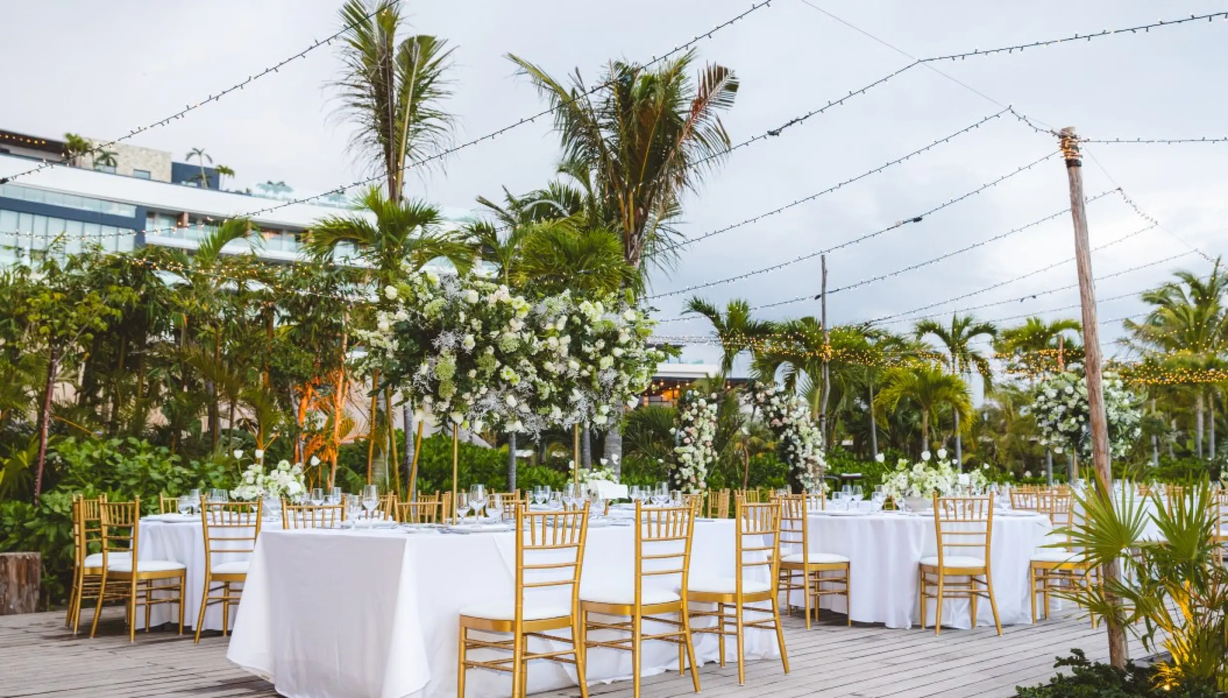 Outdoor wedding reception with white floral centerpieces and string lights at Impression Moxché, Playa Del Carmen