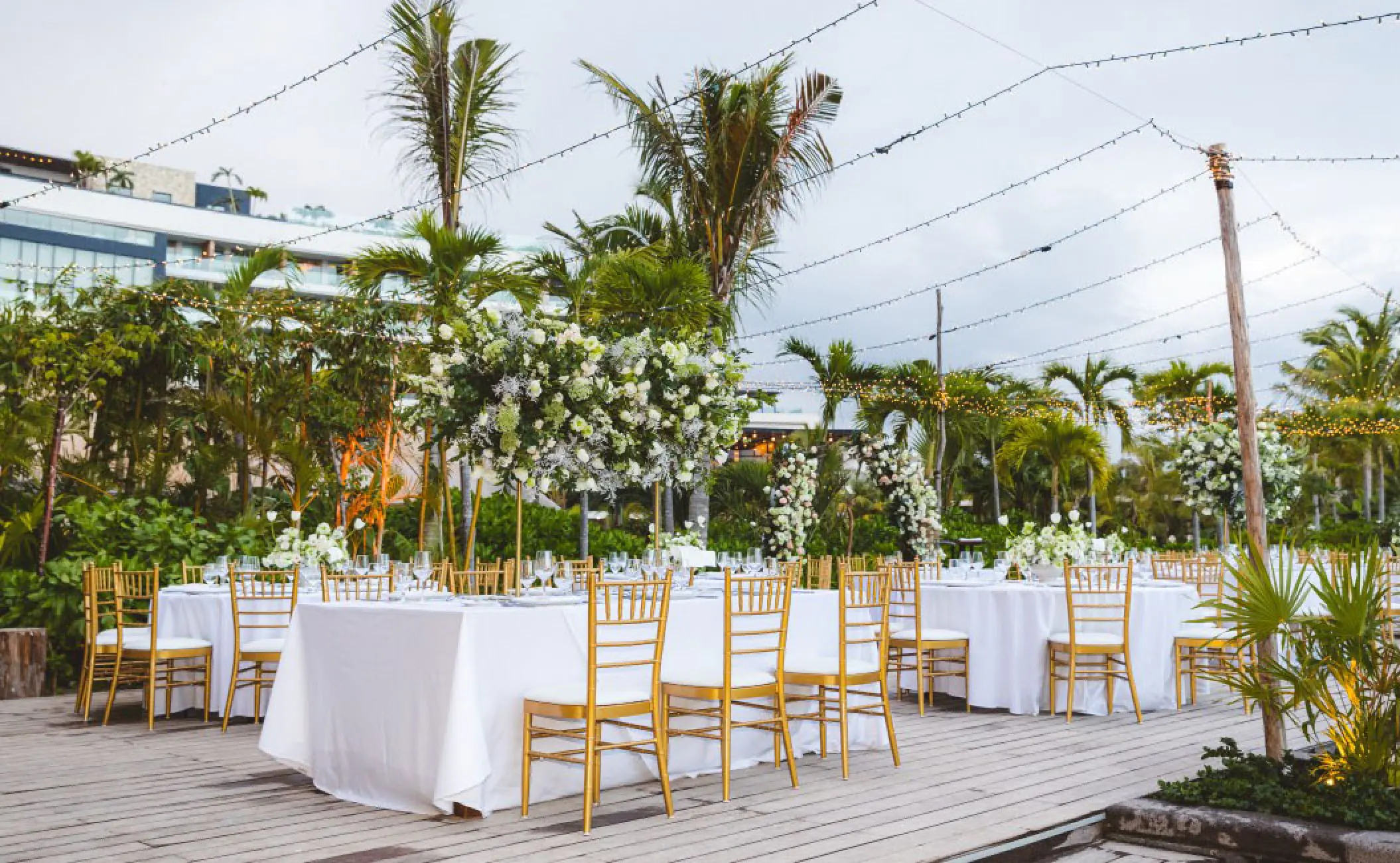 Outdoor wedding reception with white floral centerpieces and string lights at Secrets Moxche, Playa Del Carmen