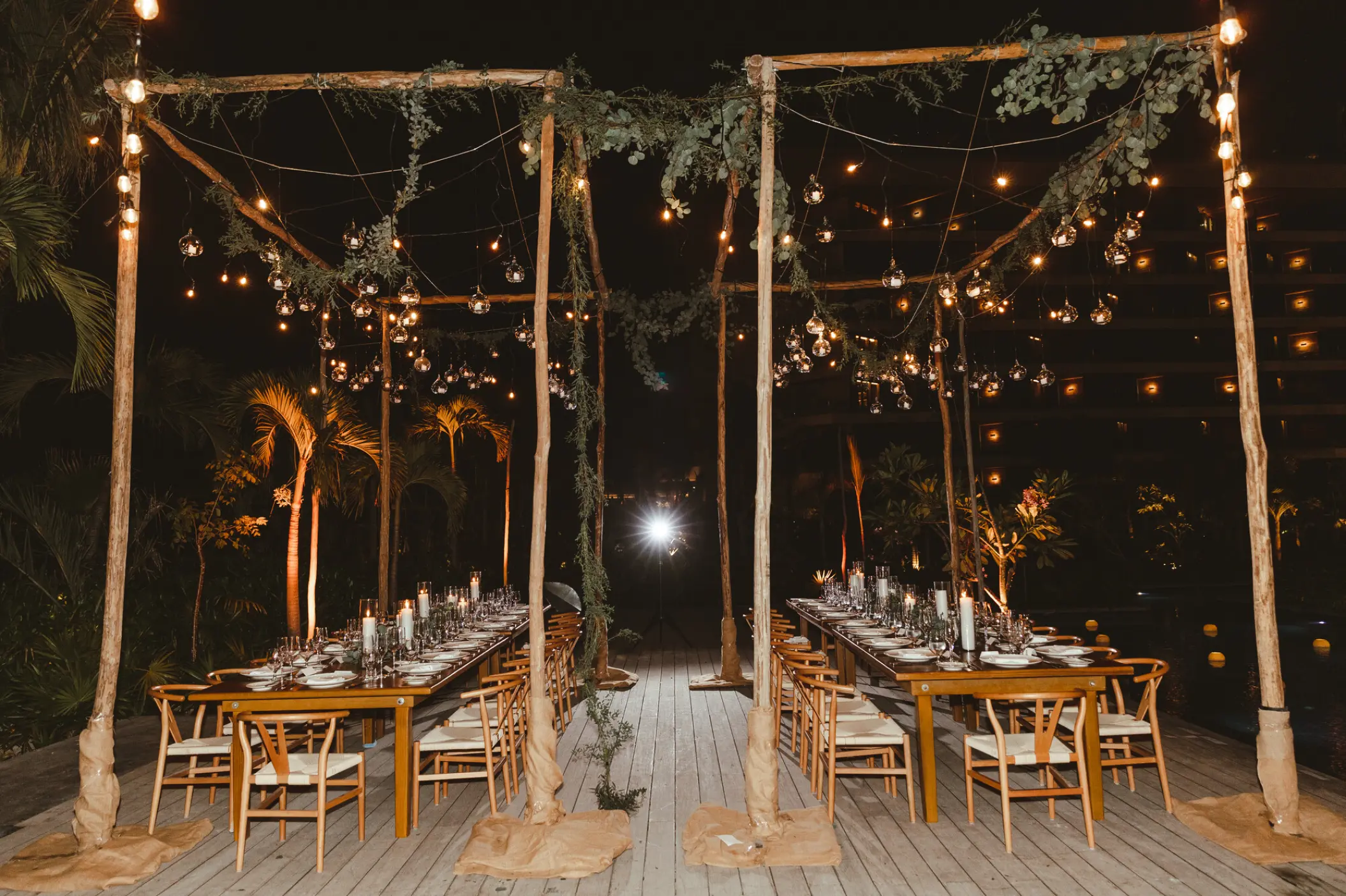 Outdoor wedding reception with long wooden tables and string lights at Secrets Moxche, Playa Del Carmen