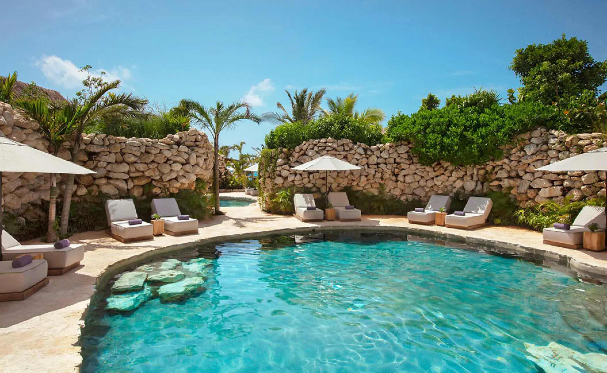 Cenote-style pool surrounded by stone walls and lounge chairs at Secrets Moxche, Playa Del Carmen
