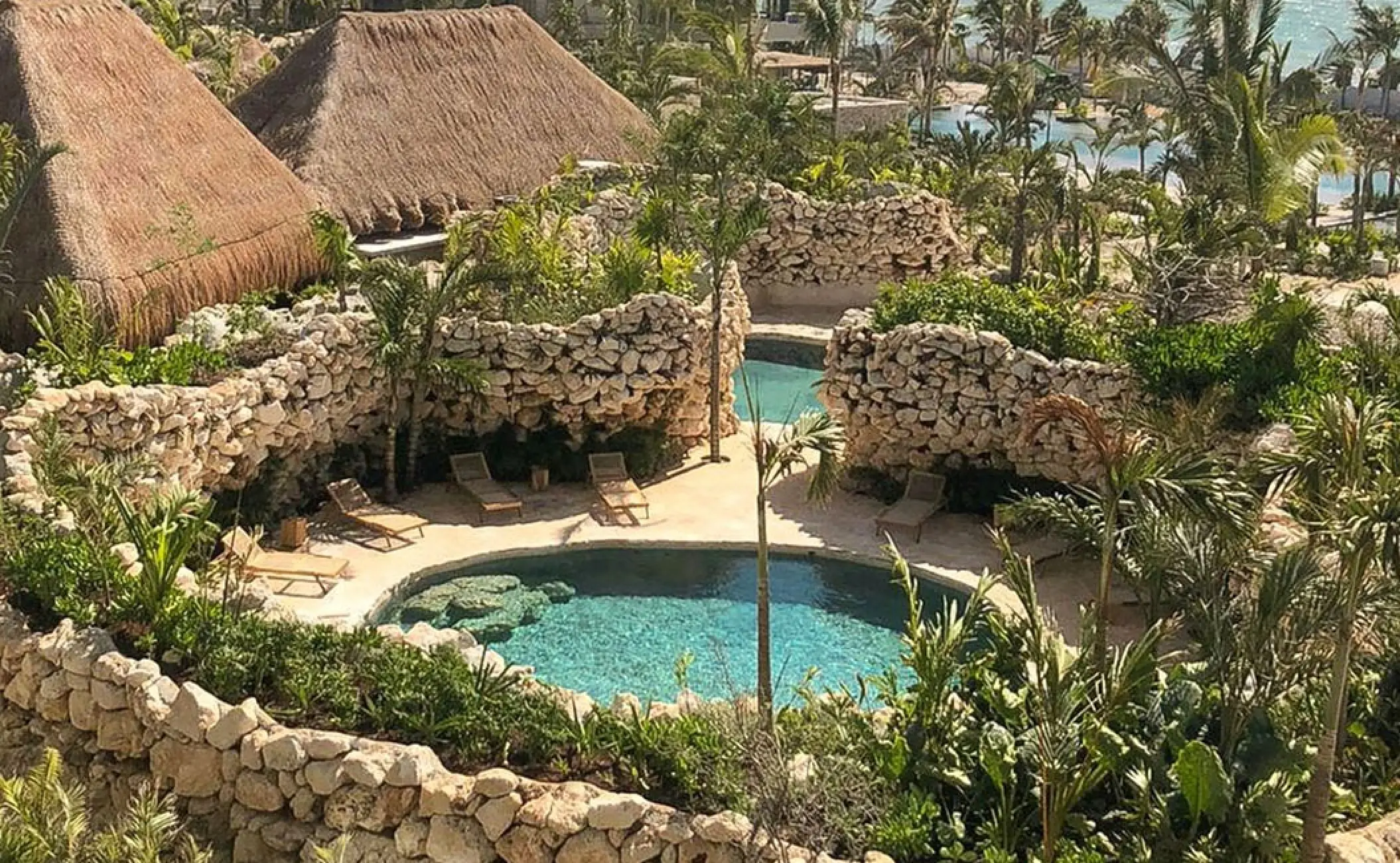 Secrets Moxche cenote-style pools surrounded by stone walls and tropical greenery, Playa Del Carmen