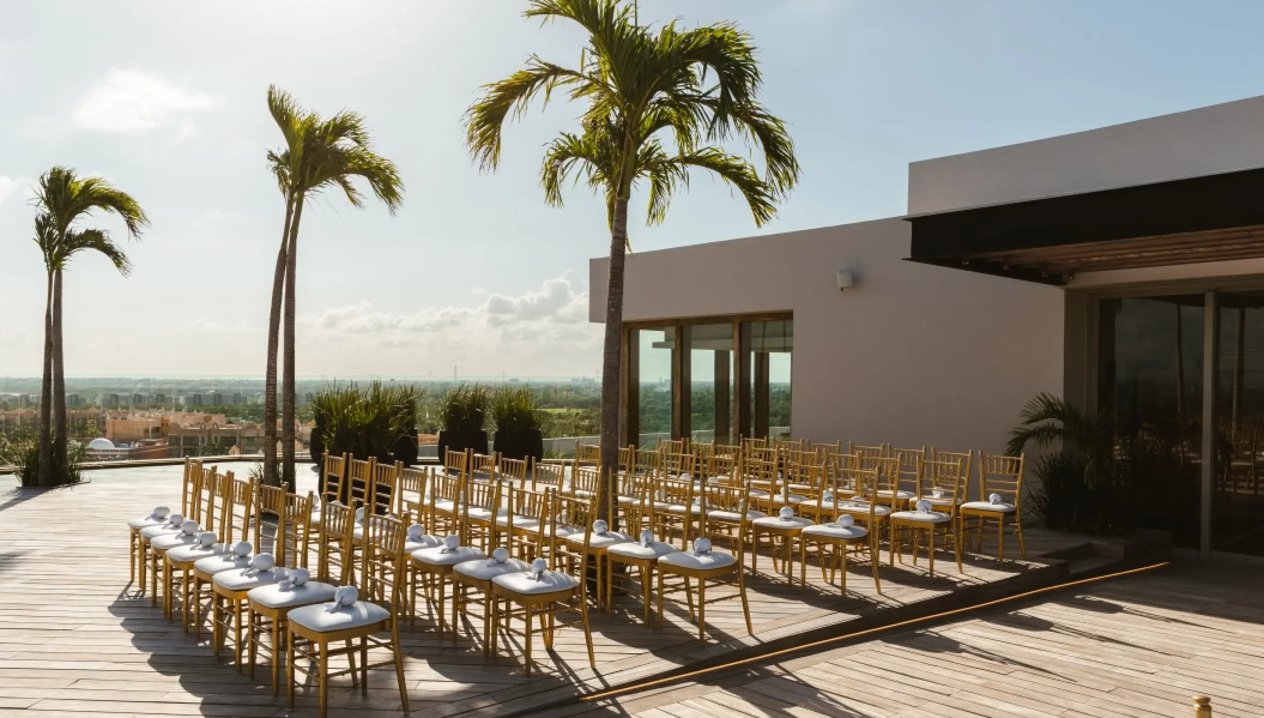 Rooftop wedding ceremony setup with gold chairs and palm trees at Impression Moxché by Secrets, Playa Del Carmen
