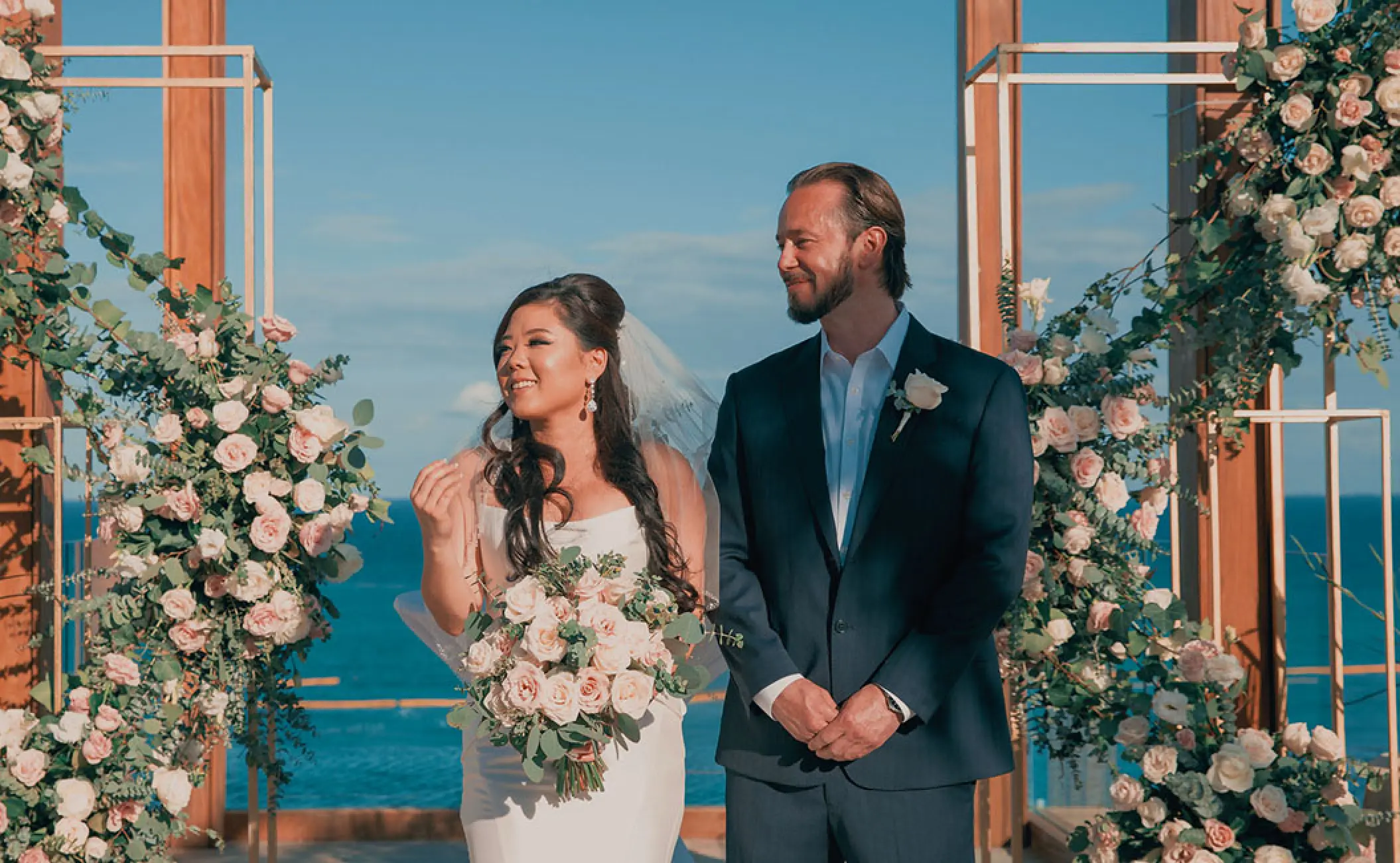 Bride and groom standing at the floral altar during their ceremony at Secrets Moxche, Playa Del Carmen