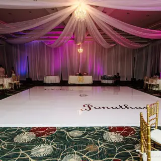 Indoor ballroom wedding reception with a white dance floor and fabric ceiling draping at Secrets Playa Mujeres, Cancun