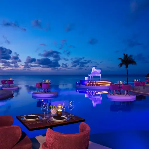 Outdoor dinner setup with purple lighting at the Secrets Riviera Cancun pool, Riviera Maya