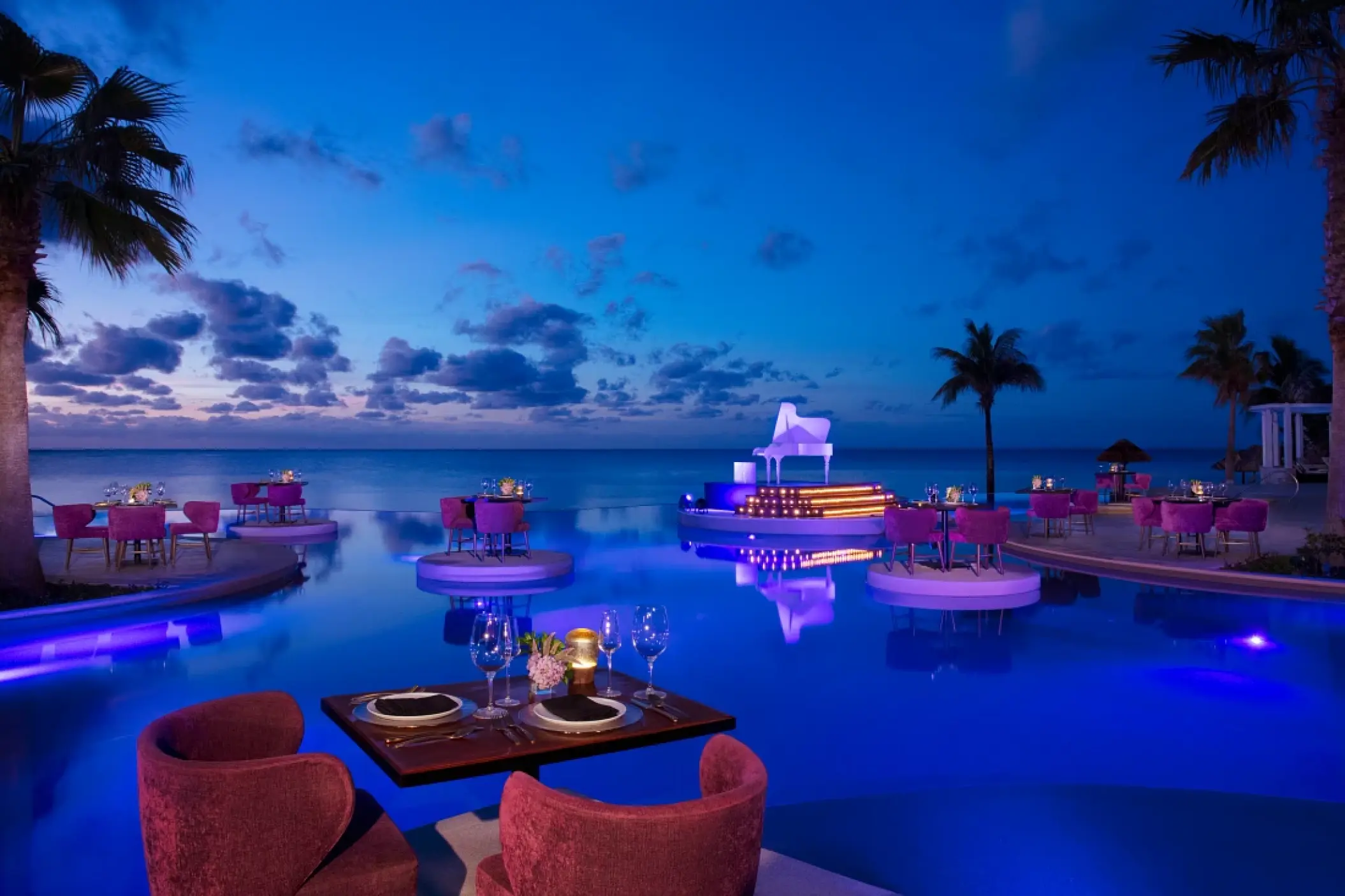 Outdoor dinner setup with purple lighting at the Secrets Riviera Cancun pool, Riviera Maya